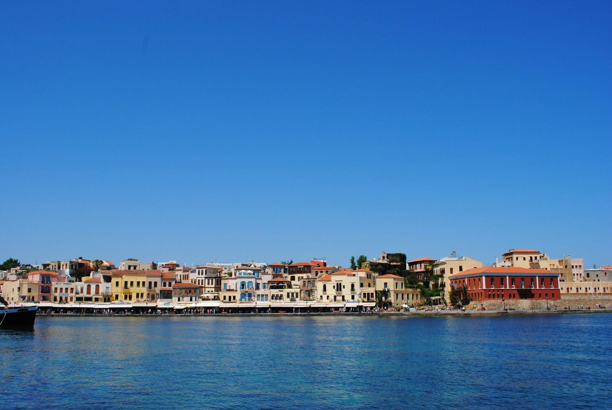 Facciata colorata di una città portuale mediterranea con edifici tradizionali che si affacciano su un mare turchese