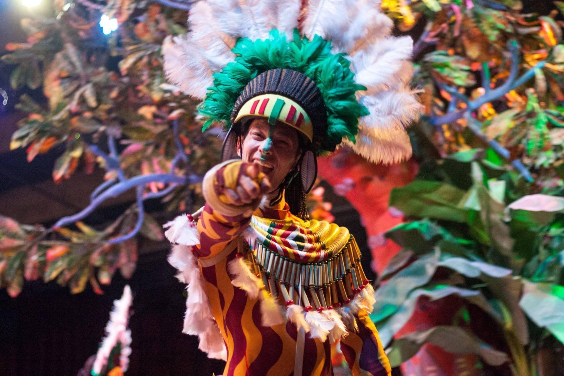 Tänzerin in farbenprächtiger Tracht mit grünem Federkopfschmuck bei einer brasilianischen Festparade