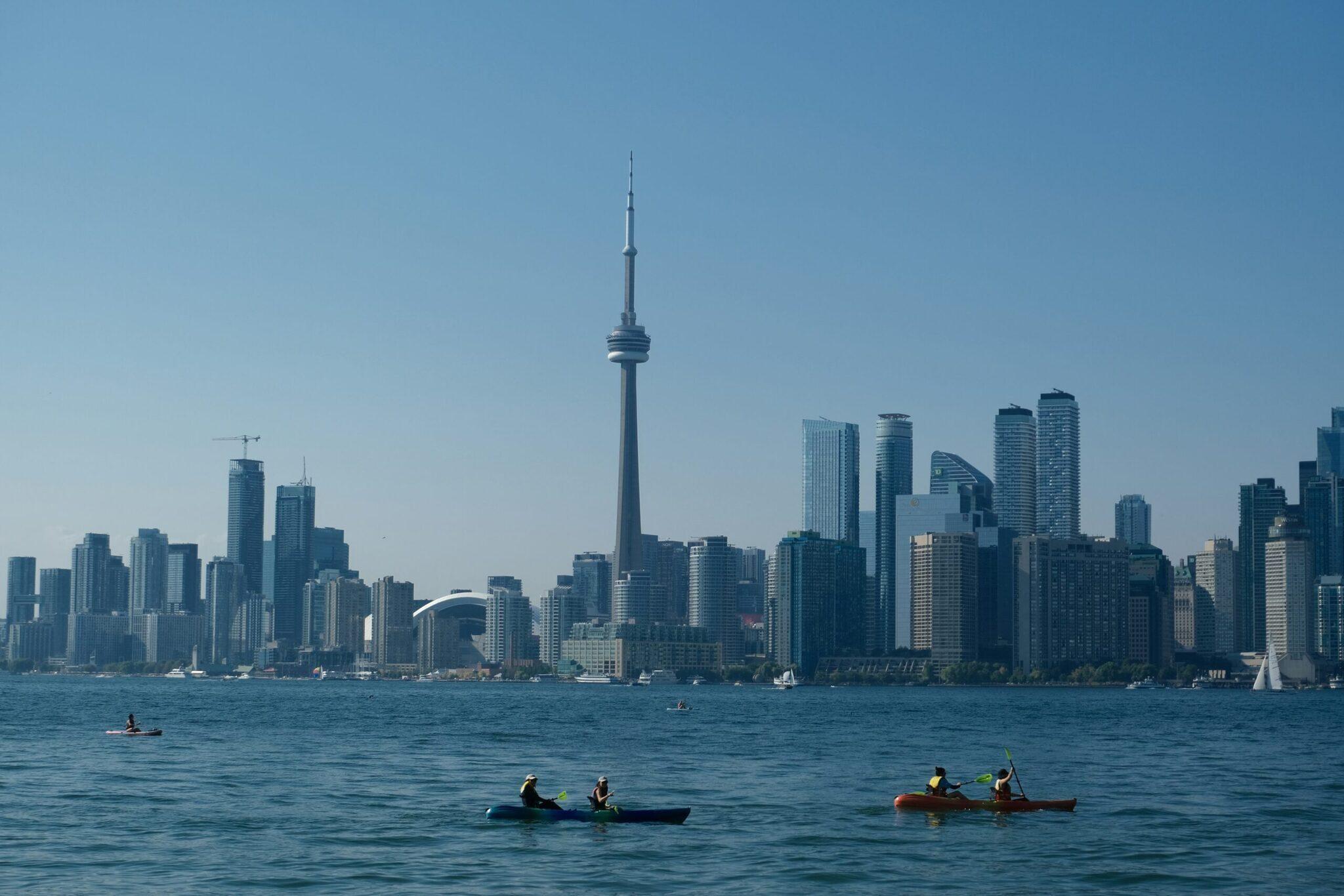 Vista panoramica di uno skyline urbano con torre caratteristica dal lago, con kayakisti in primo piano
