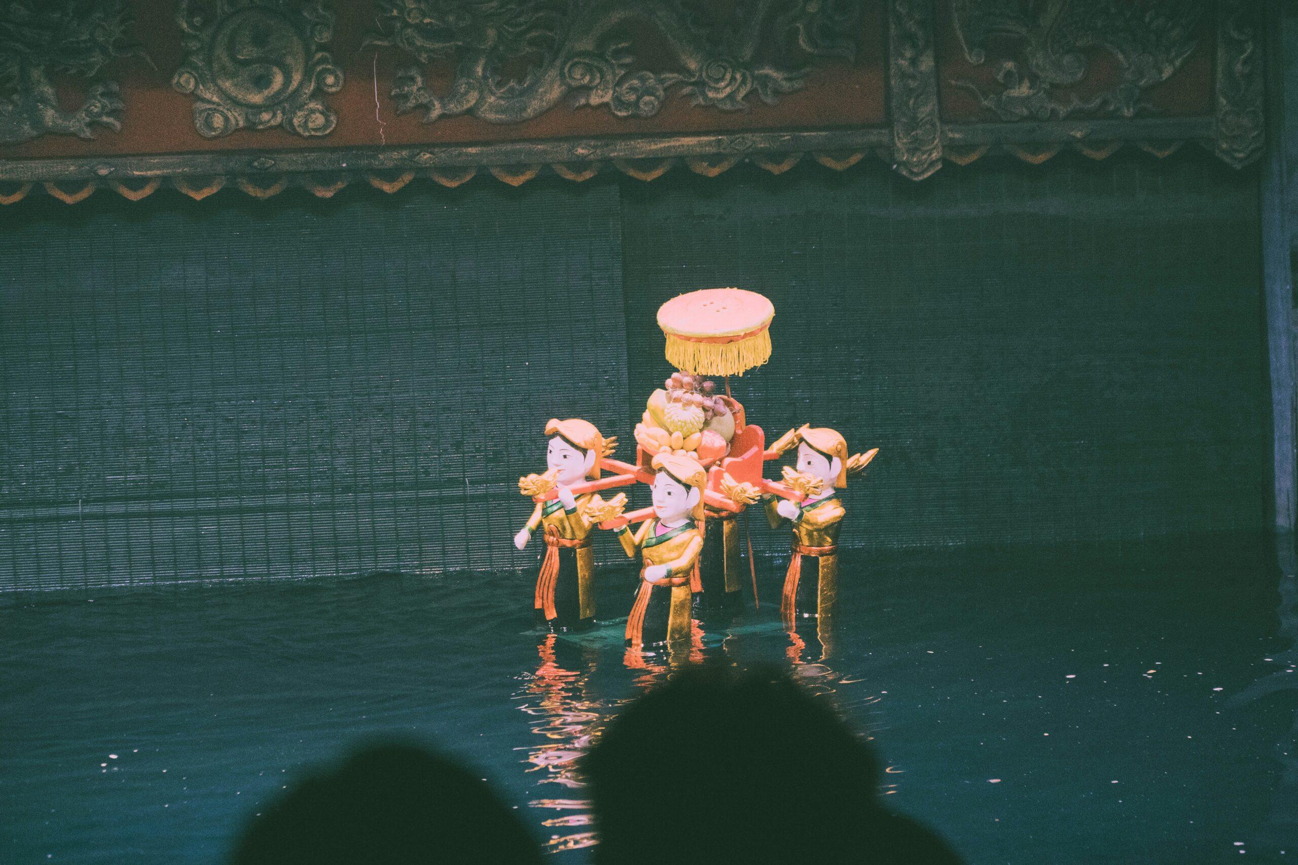 Espectáculo tradicional vietnamita de marionetas acuáticas con personajes en trajes dorados y decorados de colores