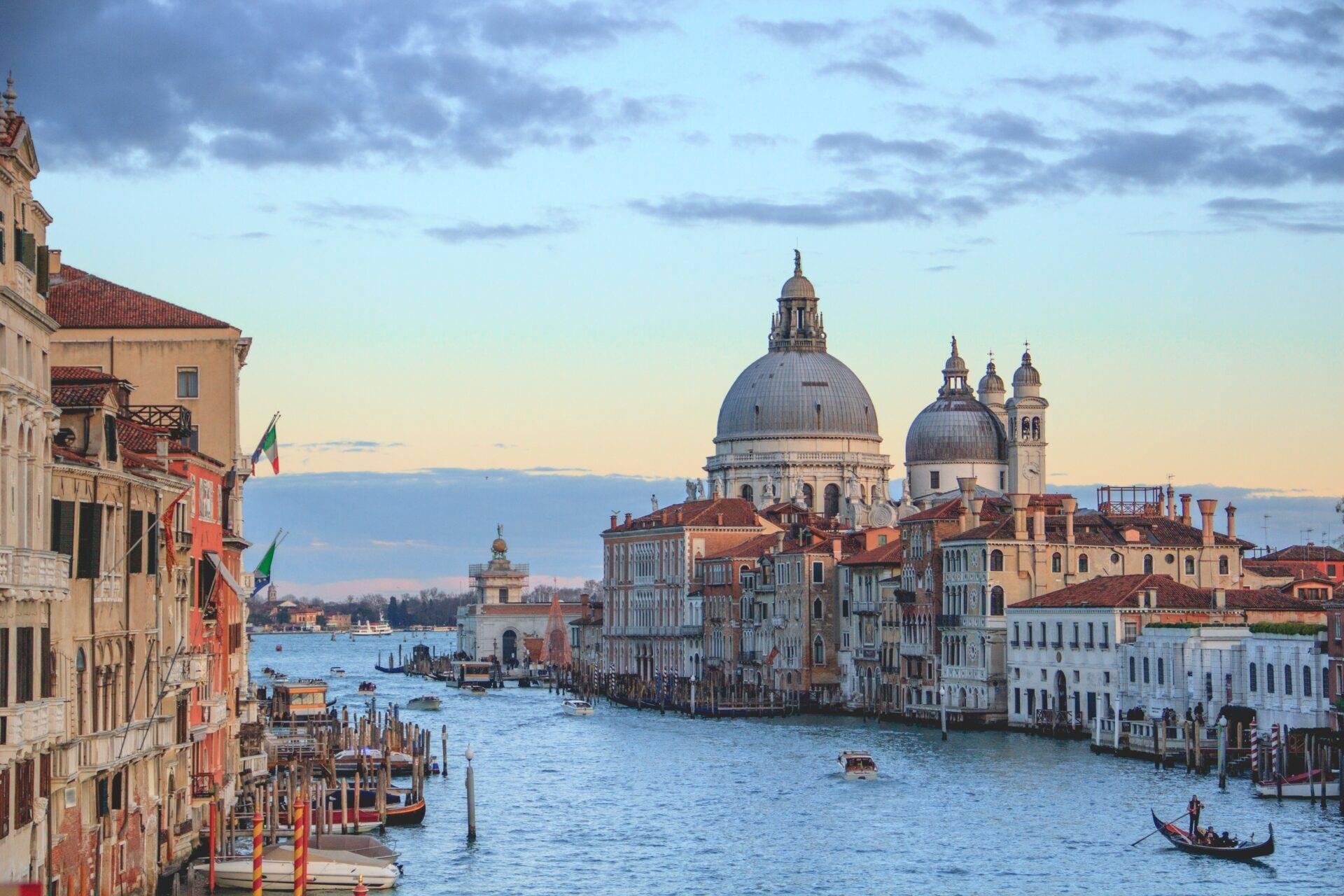 View of the Grand Canal with a domed basilica, Venetian palaces and a gondola in the golden light of dusk