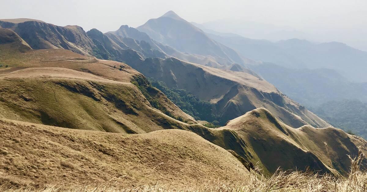 Catena di montagne verdeggianti e brulle con cime scoscese e valli nebbiose sullo sfondo
