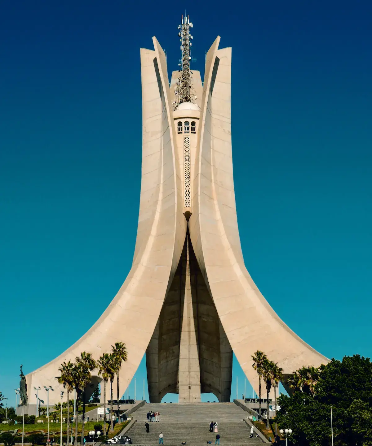 Un monumento moderno blanco de formas geométricas imponentes con una torre central, bajo un cielo azul despejado