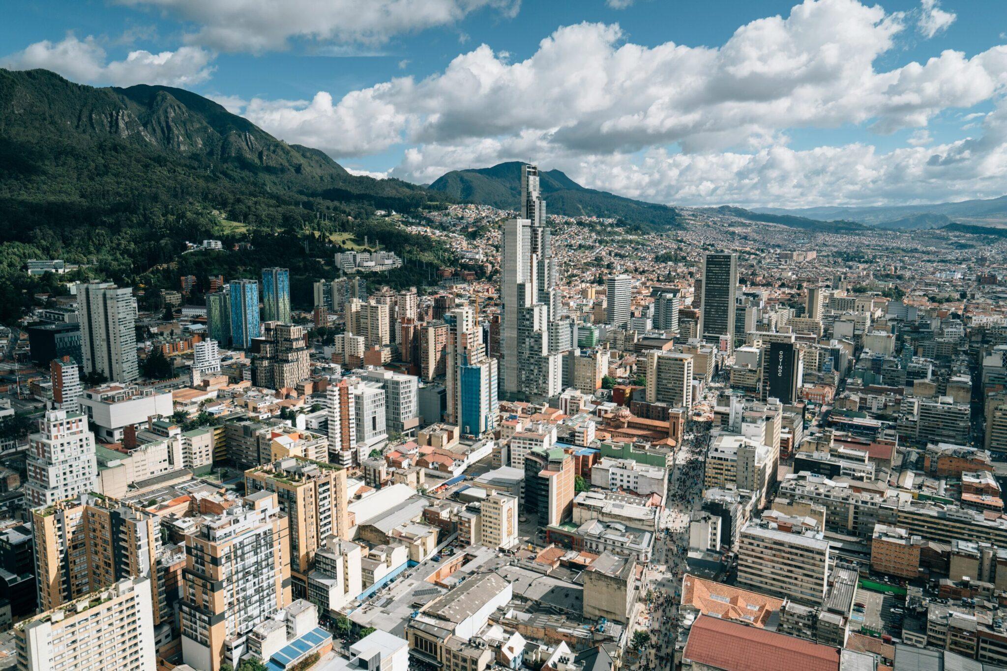 Vista aérea de una gran ciudad andina rodeada de montañas verdes bajo un cielo despejado