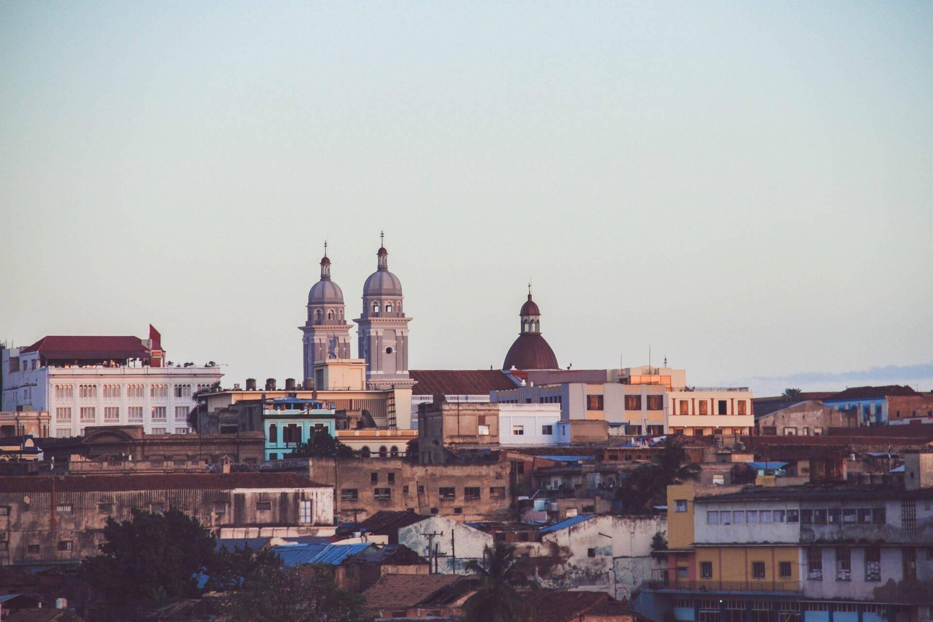 Vista panoramica di una città costiera colorata con chiese dalle cupole blu che dominano l’architettura coloniale