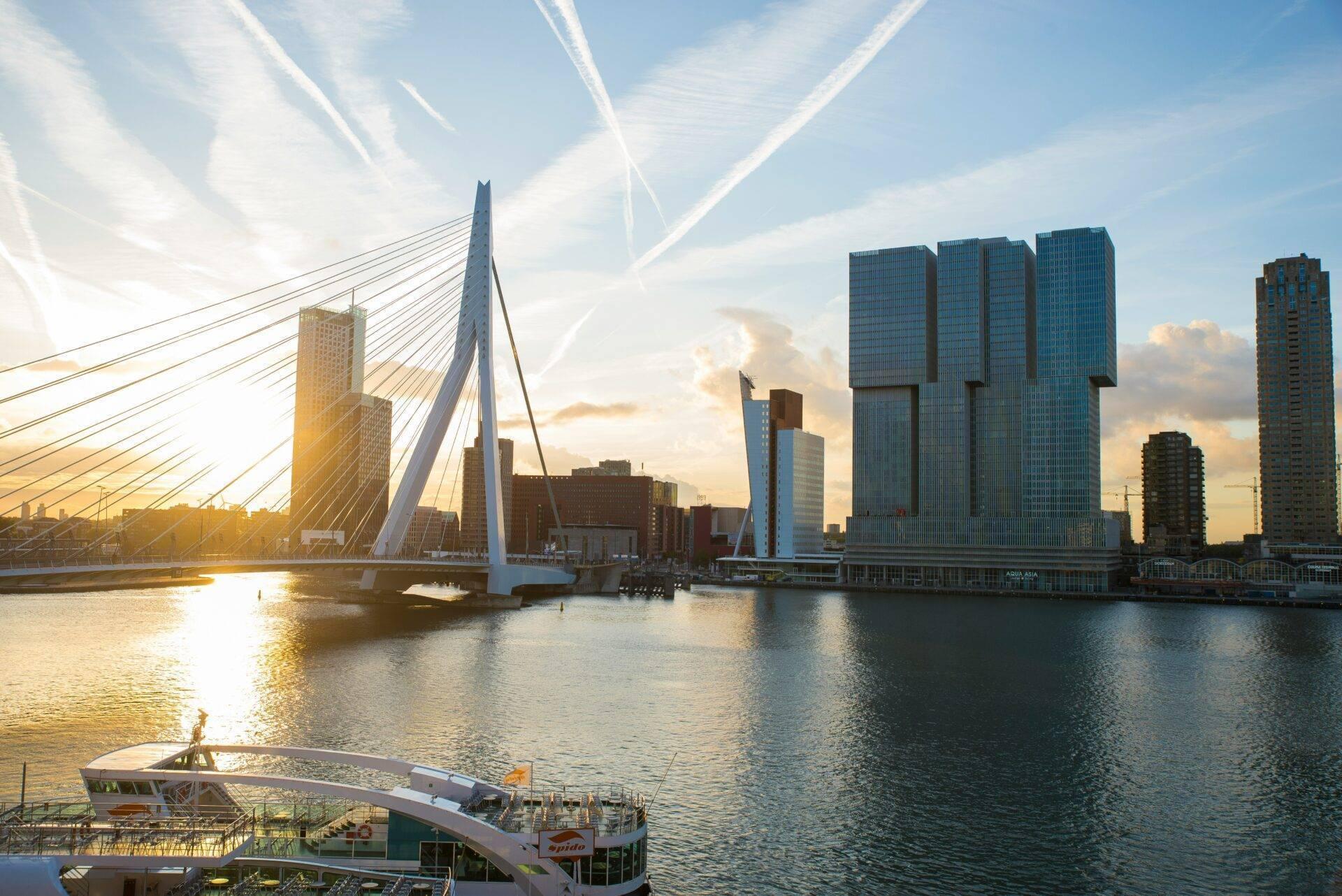 Moderne weiße Brücke über einen Kanal mit Wolkenkratzern und Schiffen im Sonnenuntergang