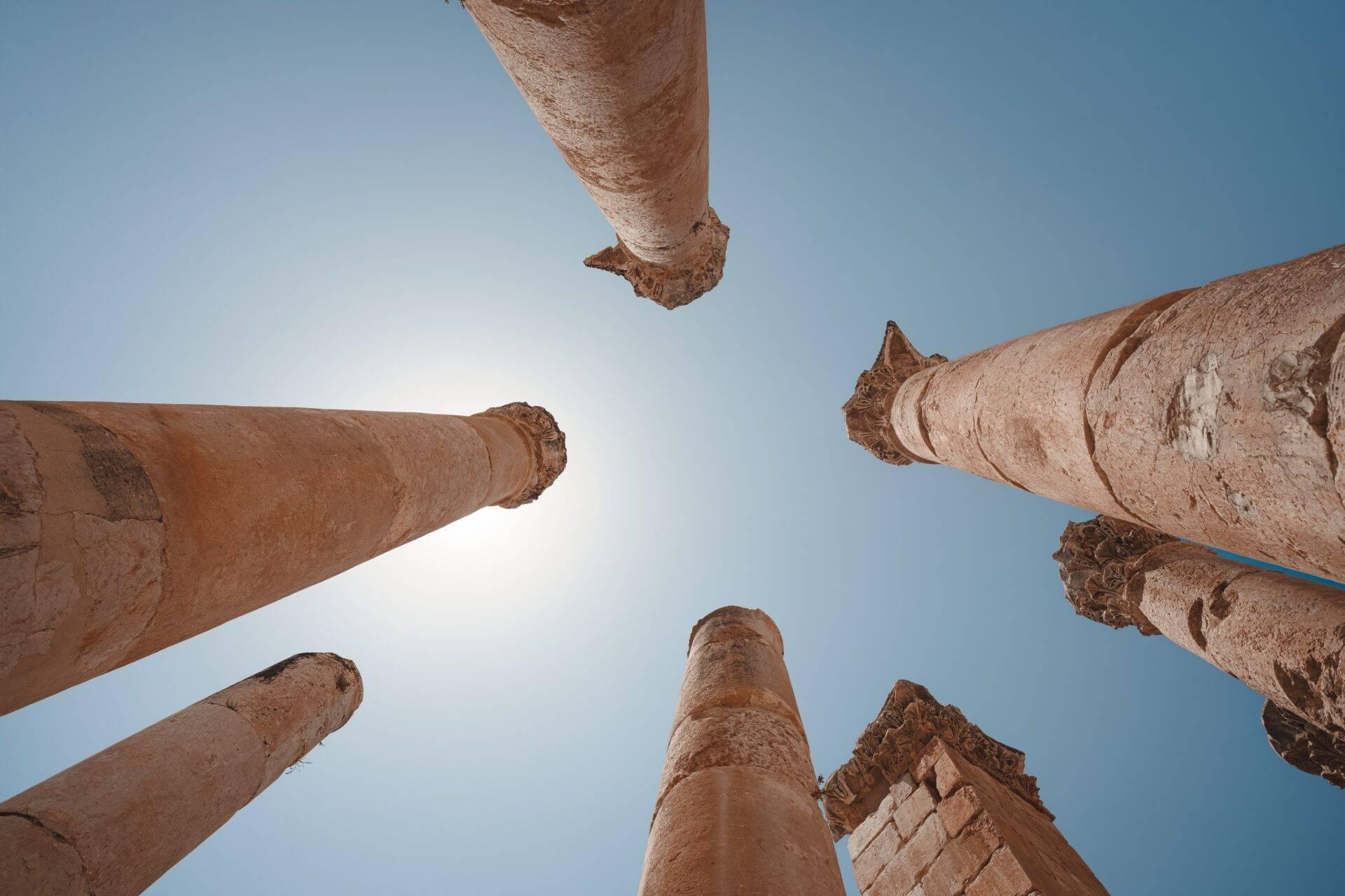 Vista en picado de columnas de piedra antiguas y monumentales contra un cielo azul despejado
