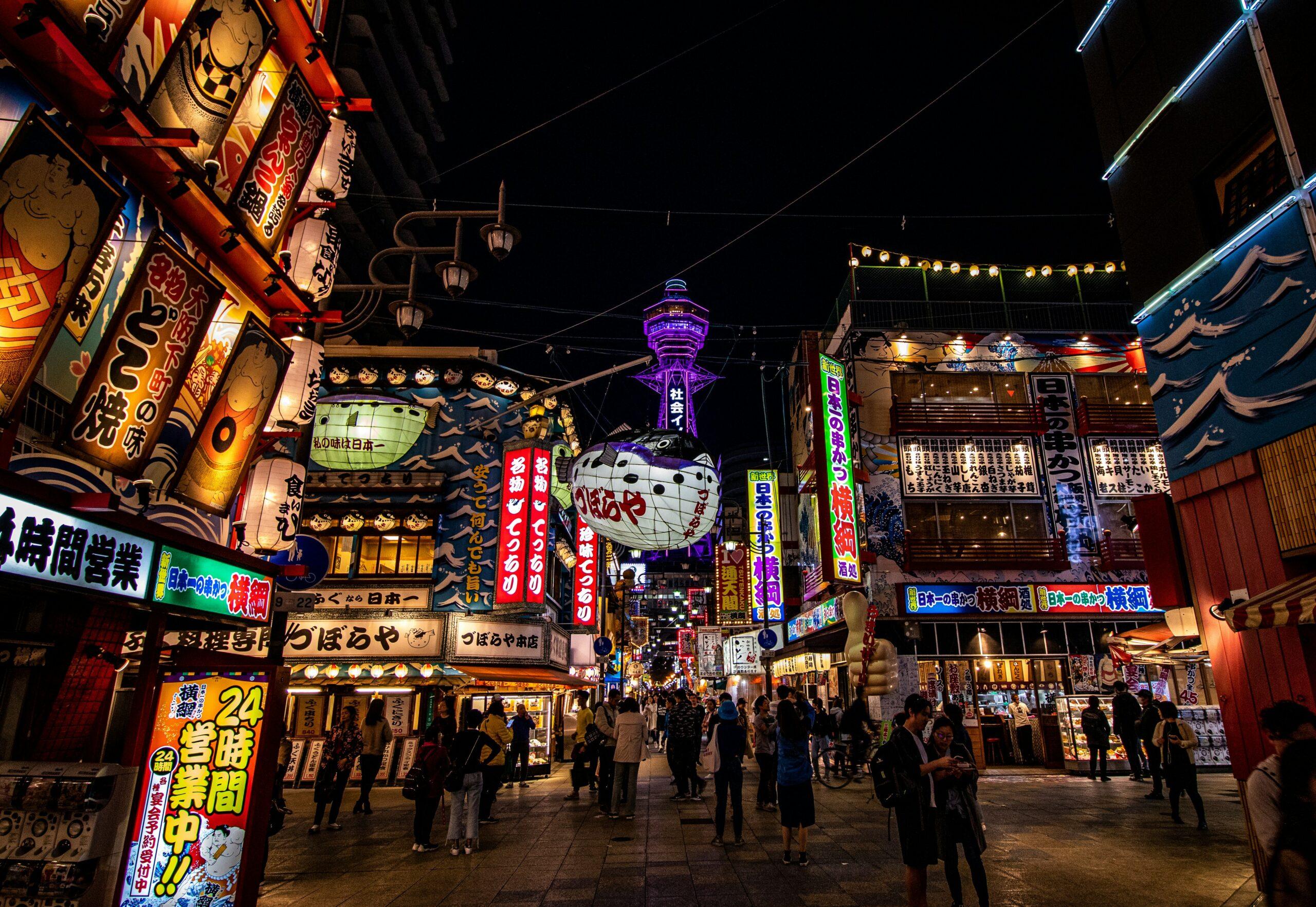 Una via dello shopping giapponese animata di notte con facciate illuminate, insegne colorate e architettura tradizionale