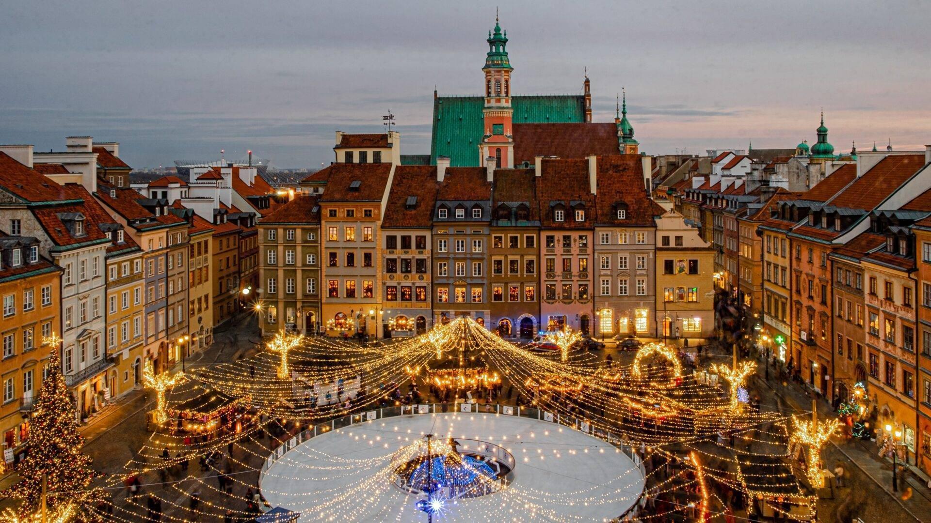Una plaza histórica iluminada con miles de luces doradas, una pista de hielo central y edificios de colores