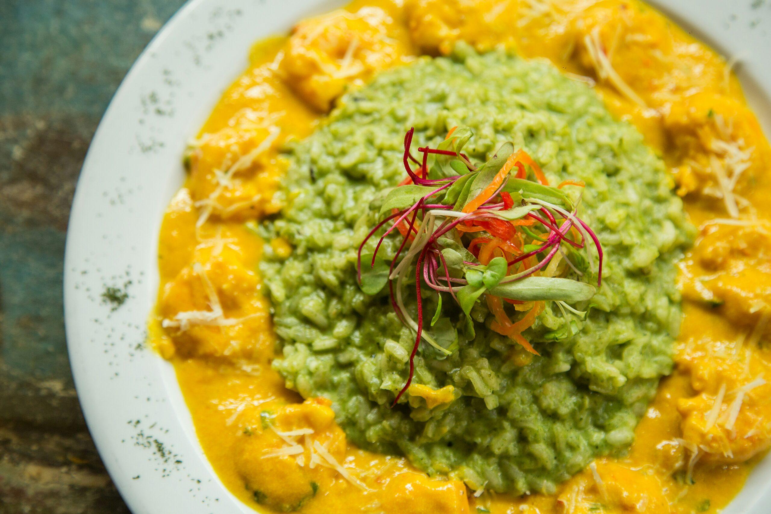 Assiette de riz à la sauce verte avec légumes jaunes et garniture colorée de microgreens, cuisine péruvienne