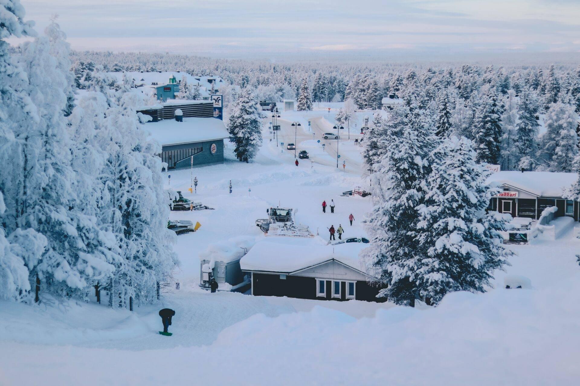 Vista aérea de una estación de esquí en Laponia con chalets, pistas nevadas y bosque de abetos cubierto de nieve