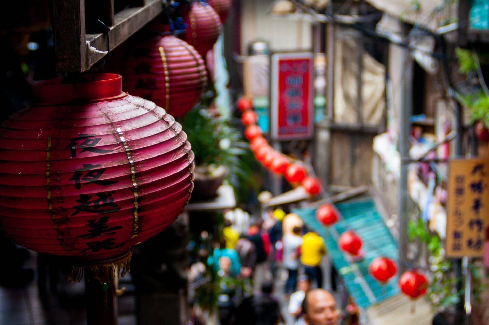 Lanterne rosse tradizionali con caratteri cinesi in un vicolo animato di una vecchia città asiatica