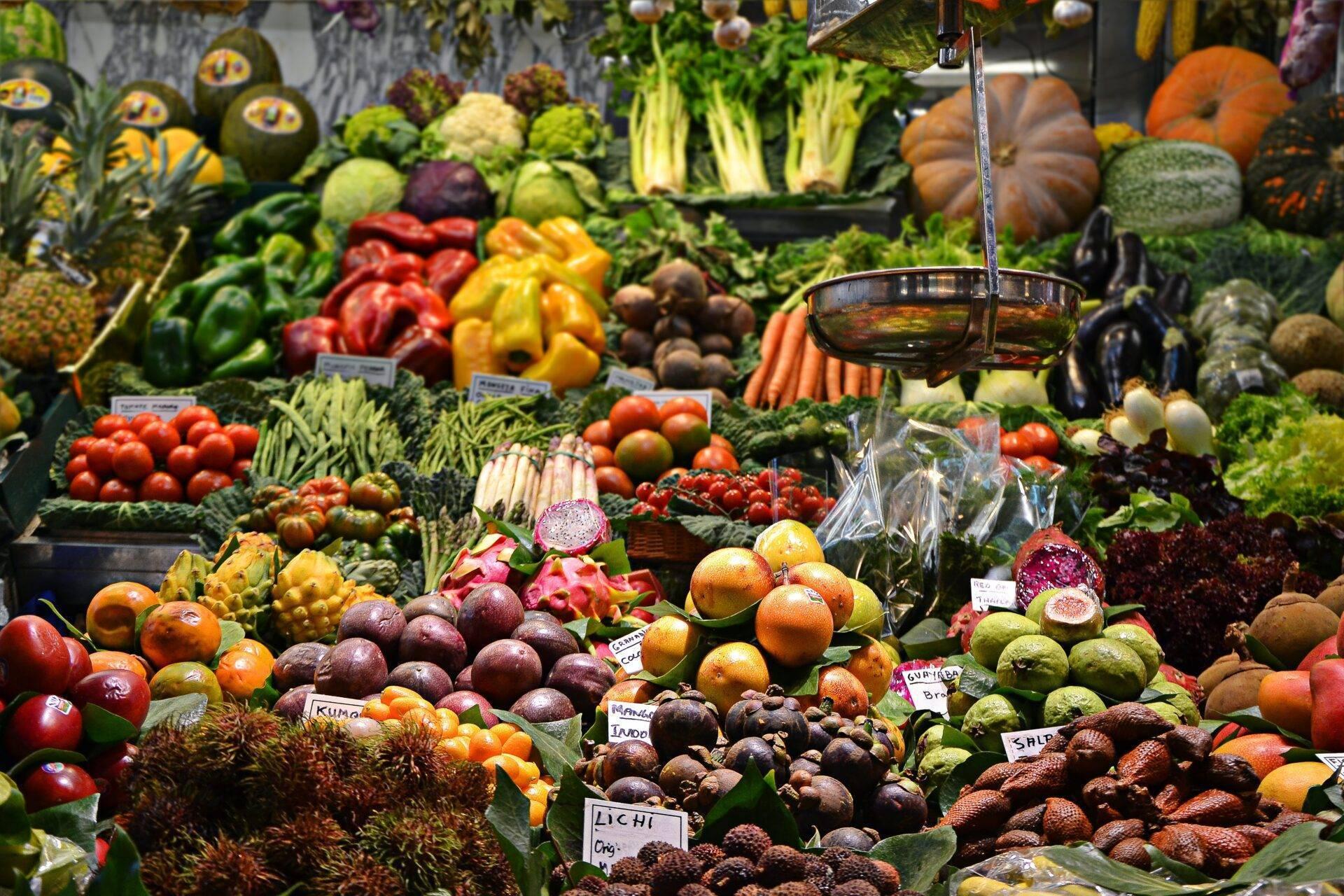 Bunter Marktstand mit frischem Obst und Gemüse auf einem Tropenmarkt, plätscherndes Wasser im Hintergrund