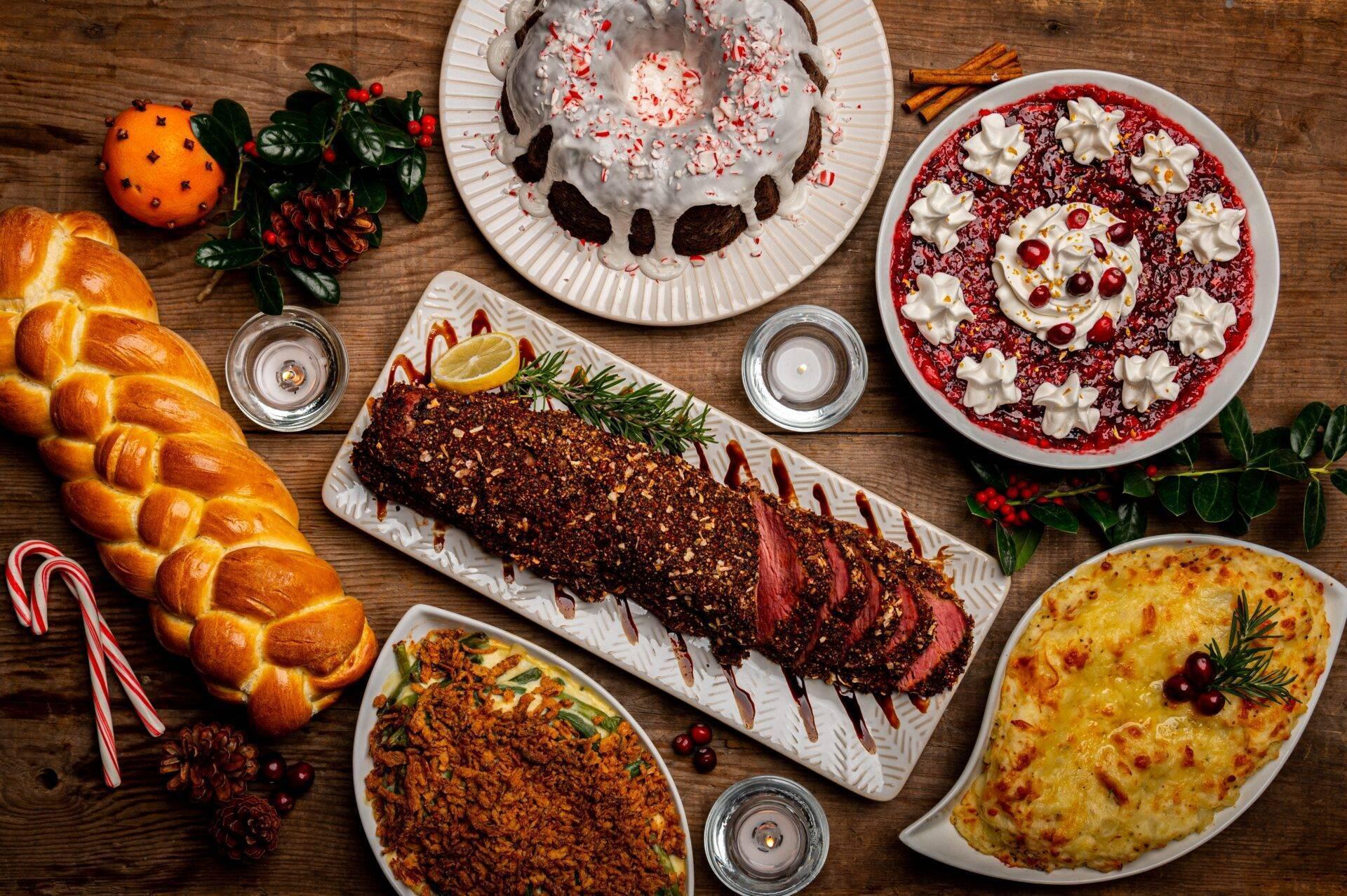 Mesa festiva invernal con panes trenzados, postres de chocolate, gratinados y decoración navideña en rojo y blanco