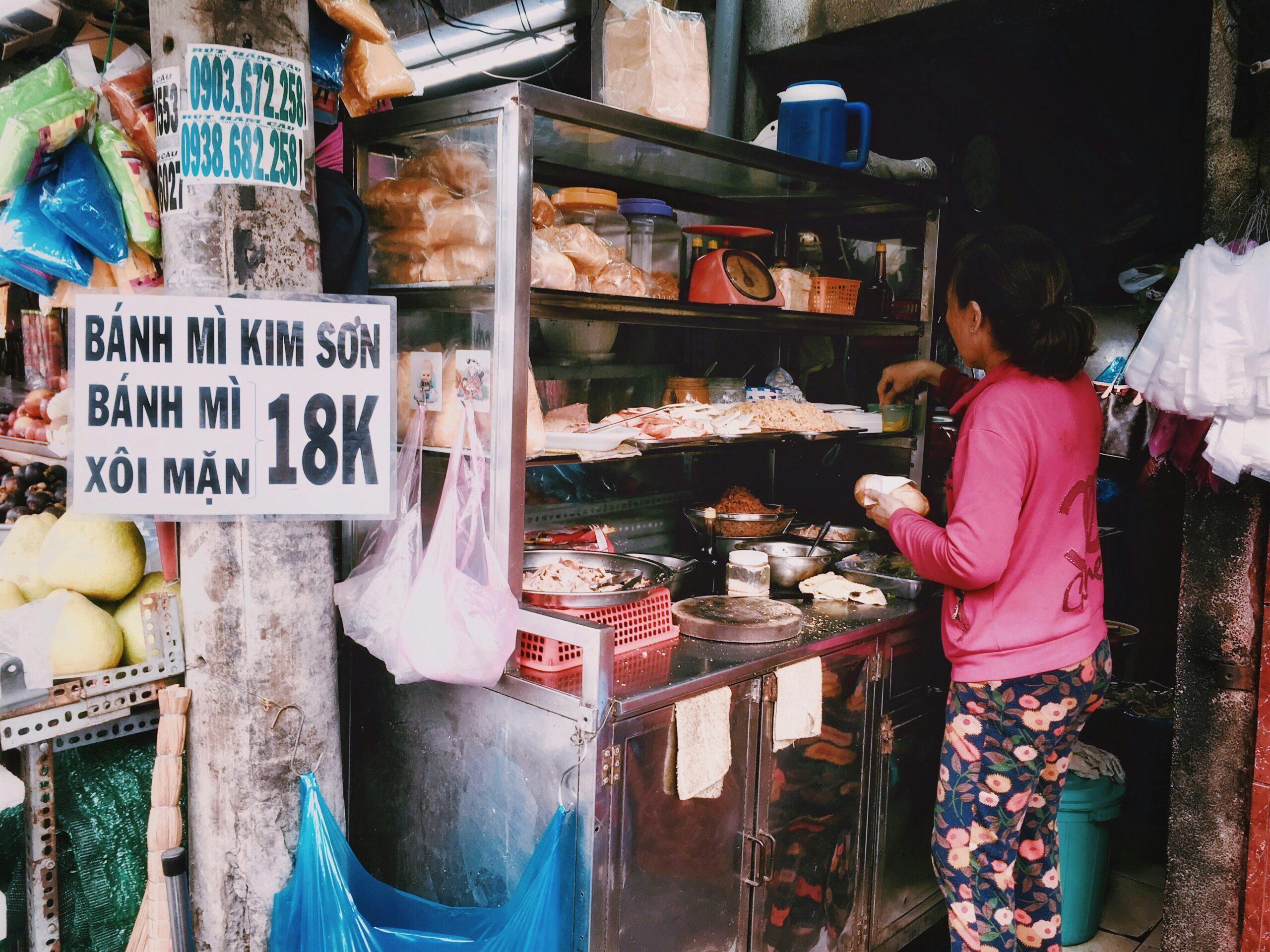 Una vendedora de street food prepara bánh mì en un pequeño puesto del Barrio Antiguo de Hanói