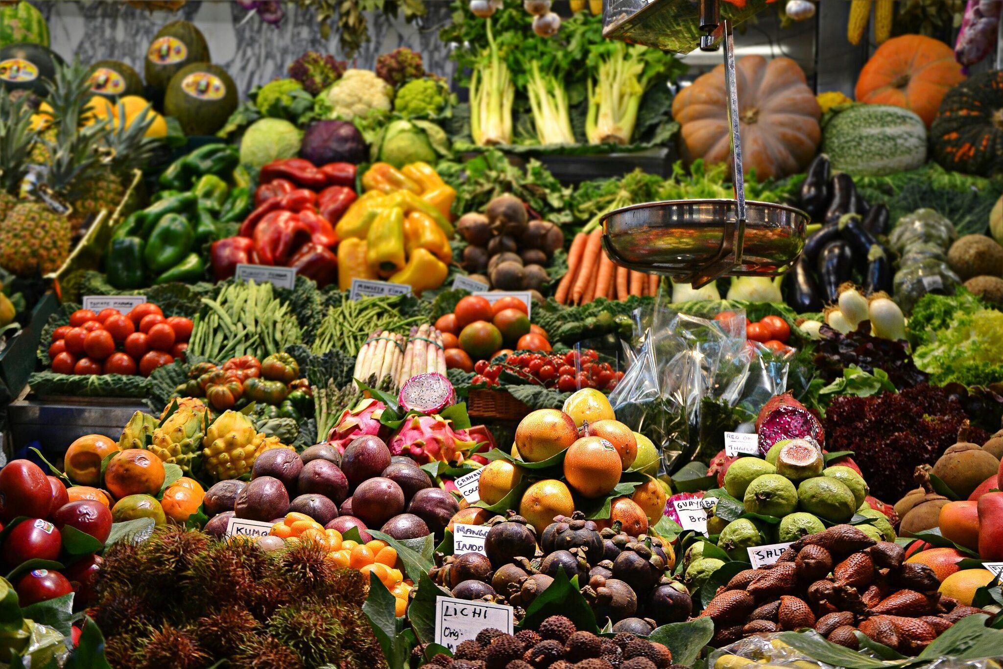 Una bancarella di mercato colorata con frutta, verdura esotica e prodotti freschi con acqua versata in continuazione