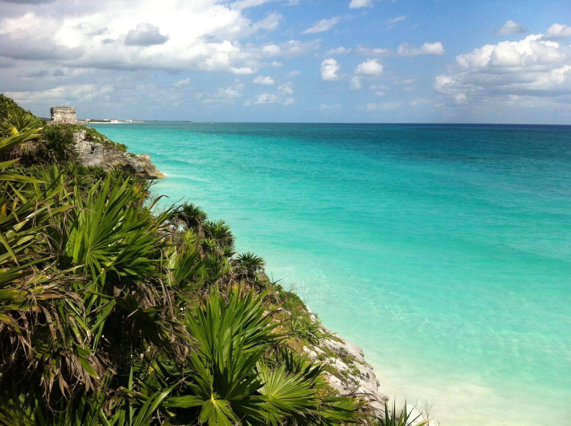 Ruinas mayas sobre un acantilado rocoso que domina un mar turquesa cristalino rodeado de vegetación tropical