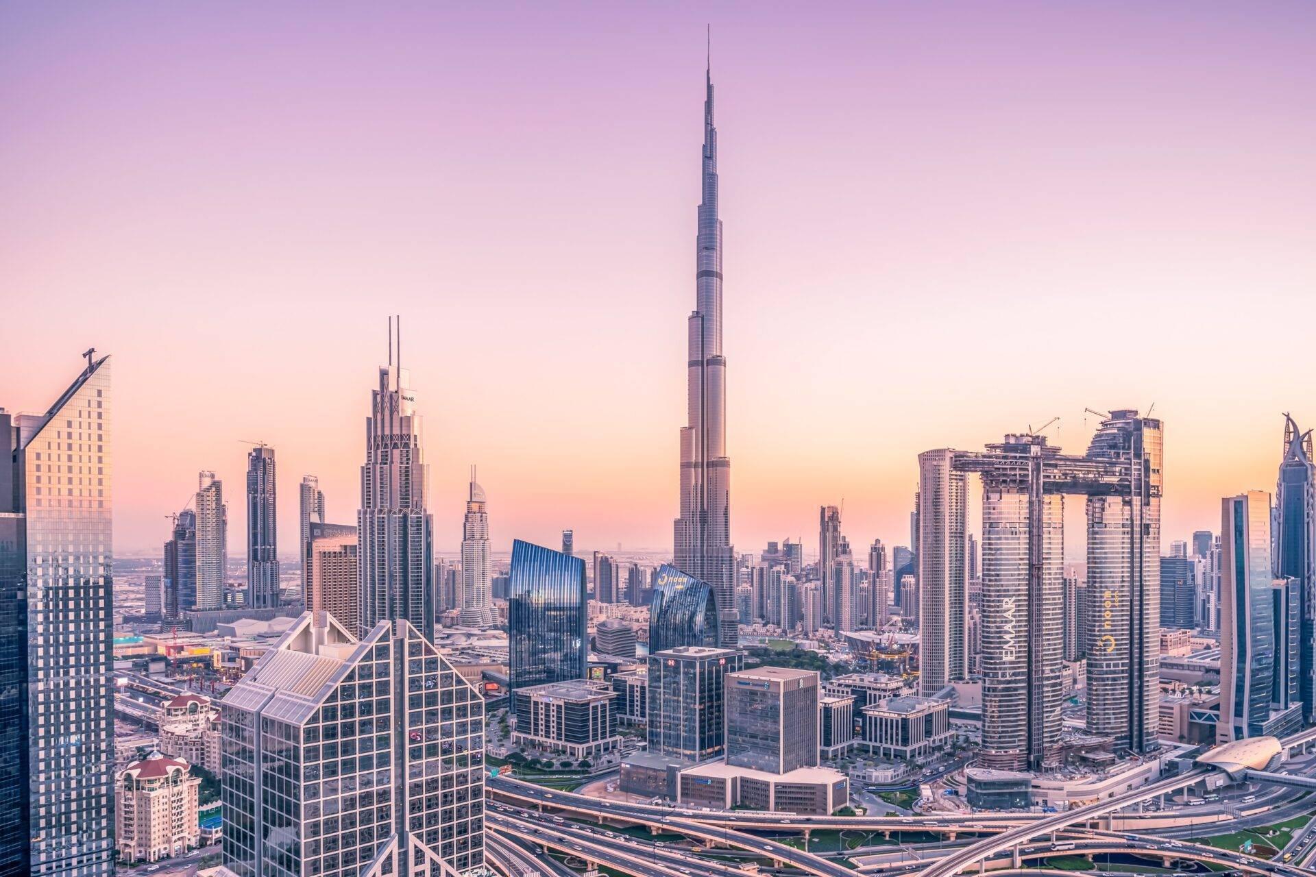 Skyline einer modernen Metropole bei Sonnenuntergang mit markanten Wolkenkratzern und weitläufigen Autobahnkreuzen