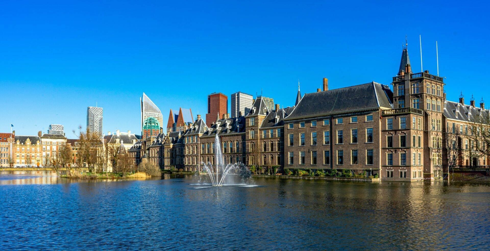 Panoramablick auf eine niederländische Stadt mit eleganten historischen Gebäuden an einem Kanal und einem Brunnen