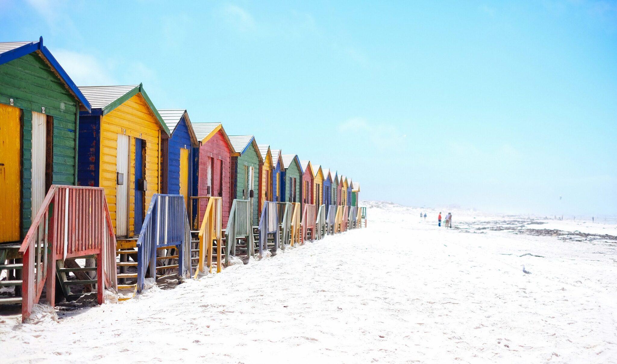 Fila di cabine da spiaggia colorate allineate sulla sabbia bianca di una spiaggia soleggiata