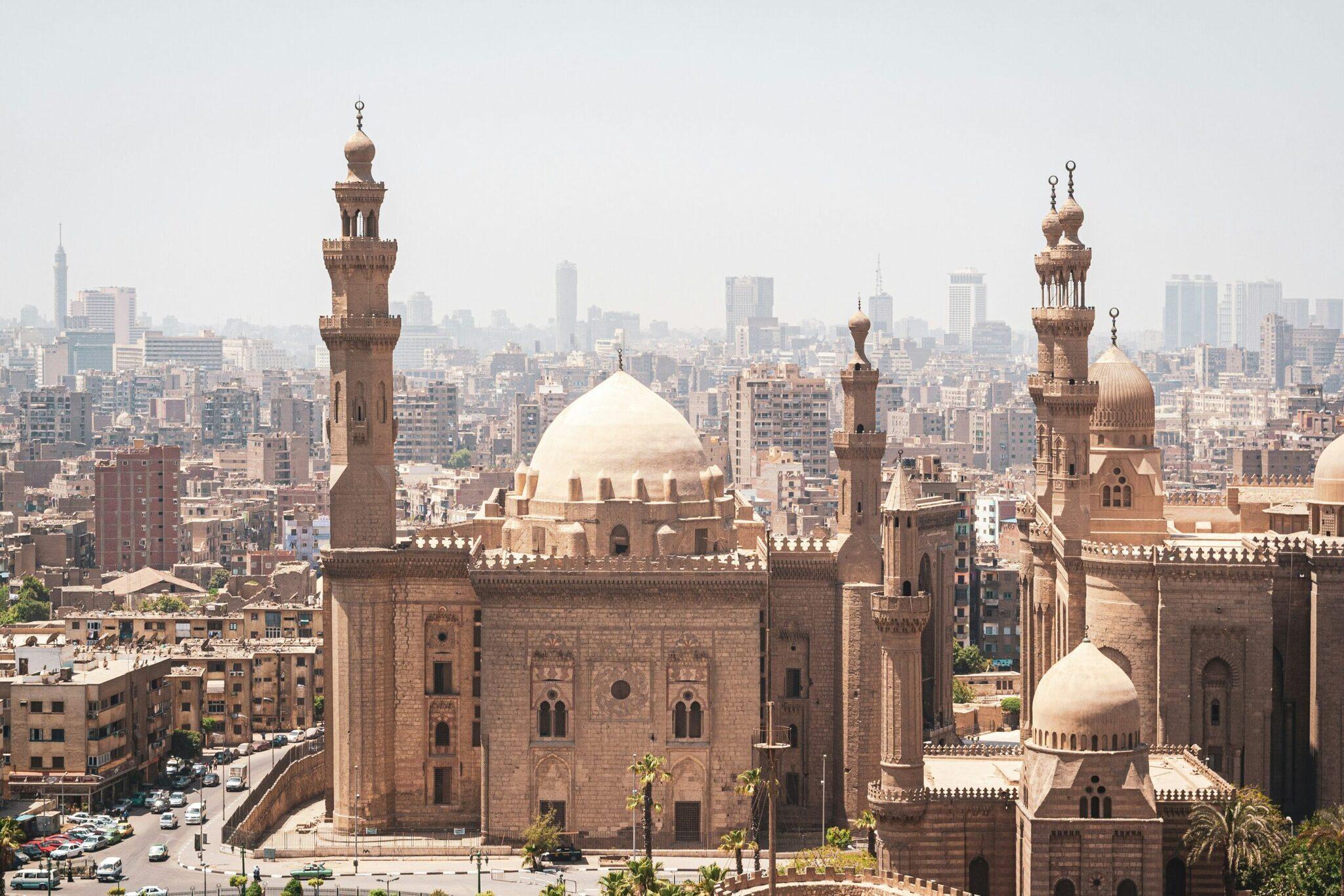 Vista panorámica de El Cairo con mezquitas históricas de cúpulas blancas y minaretes que dominan la densa silueta urbana