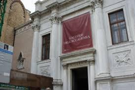 Facciata bianca di un edificio storico veneziano con stendardo rosso e dettagli architettonici classici