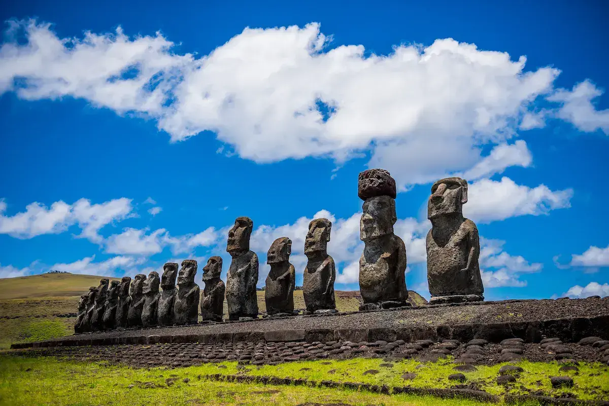 Una hilera de moáis gigantes de piedra sobre una meseta herbosa bajo un cielo azul despejado