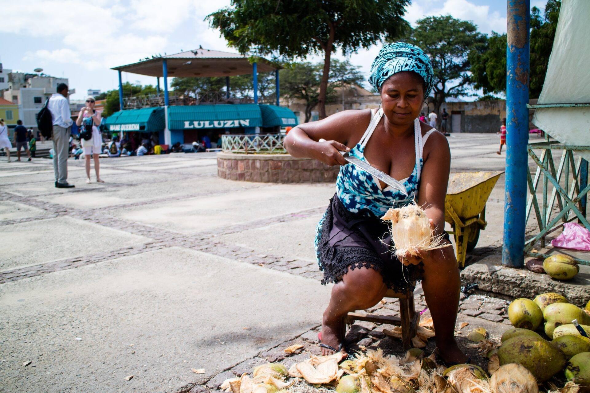Une femme prépare des noix de coco sur un marché en plein air dans une petite ville côtière