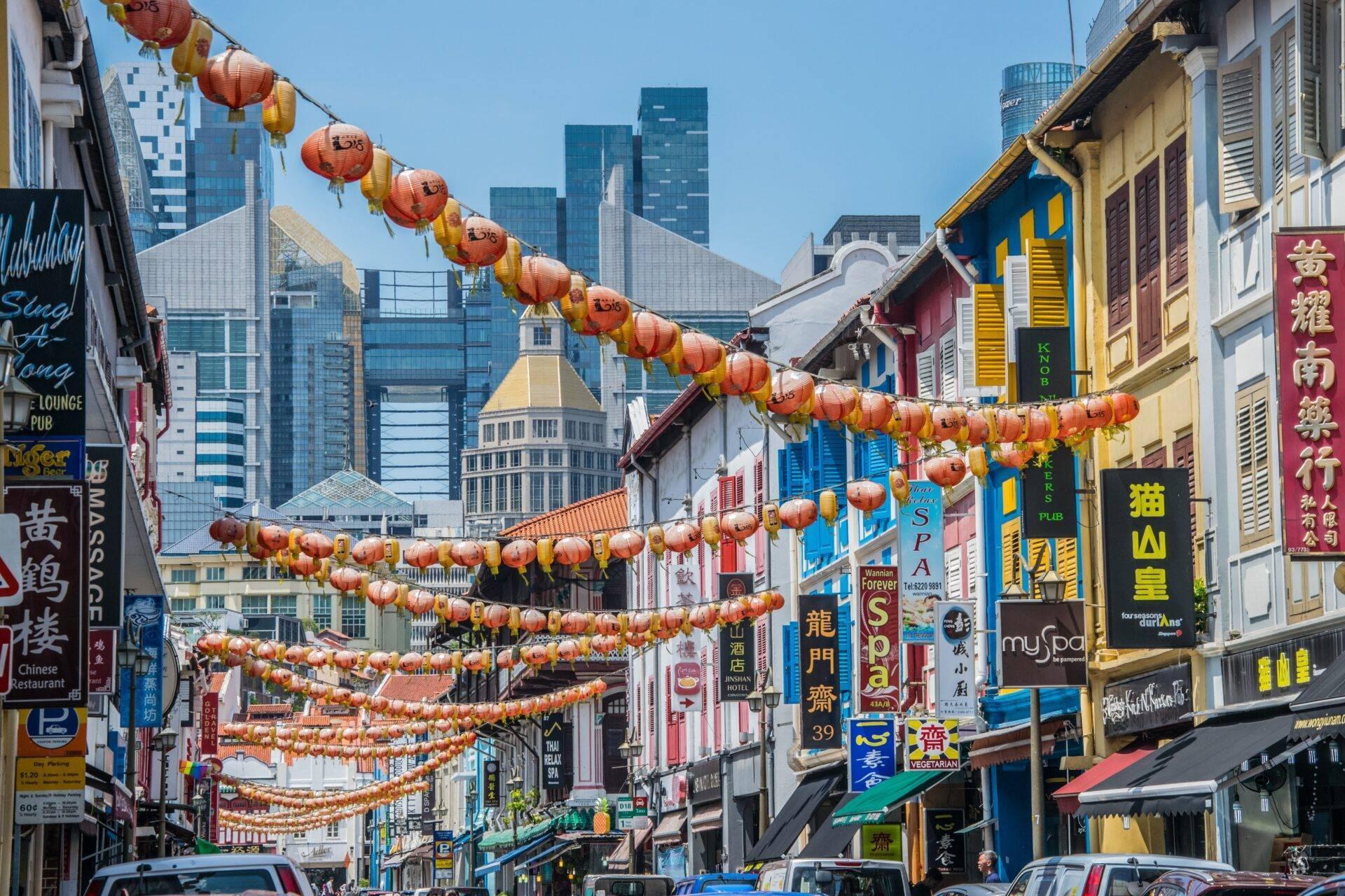 Eine farbenfrohe asiatische Einkaufsstraße, geschmückt mit traditionellen roten Laternen und modernen Hochhäusern im Hintergrund
