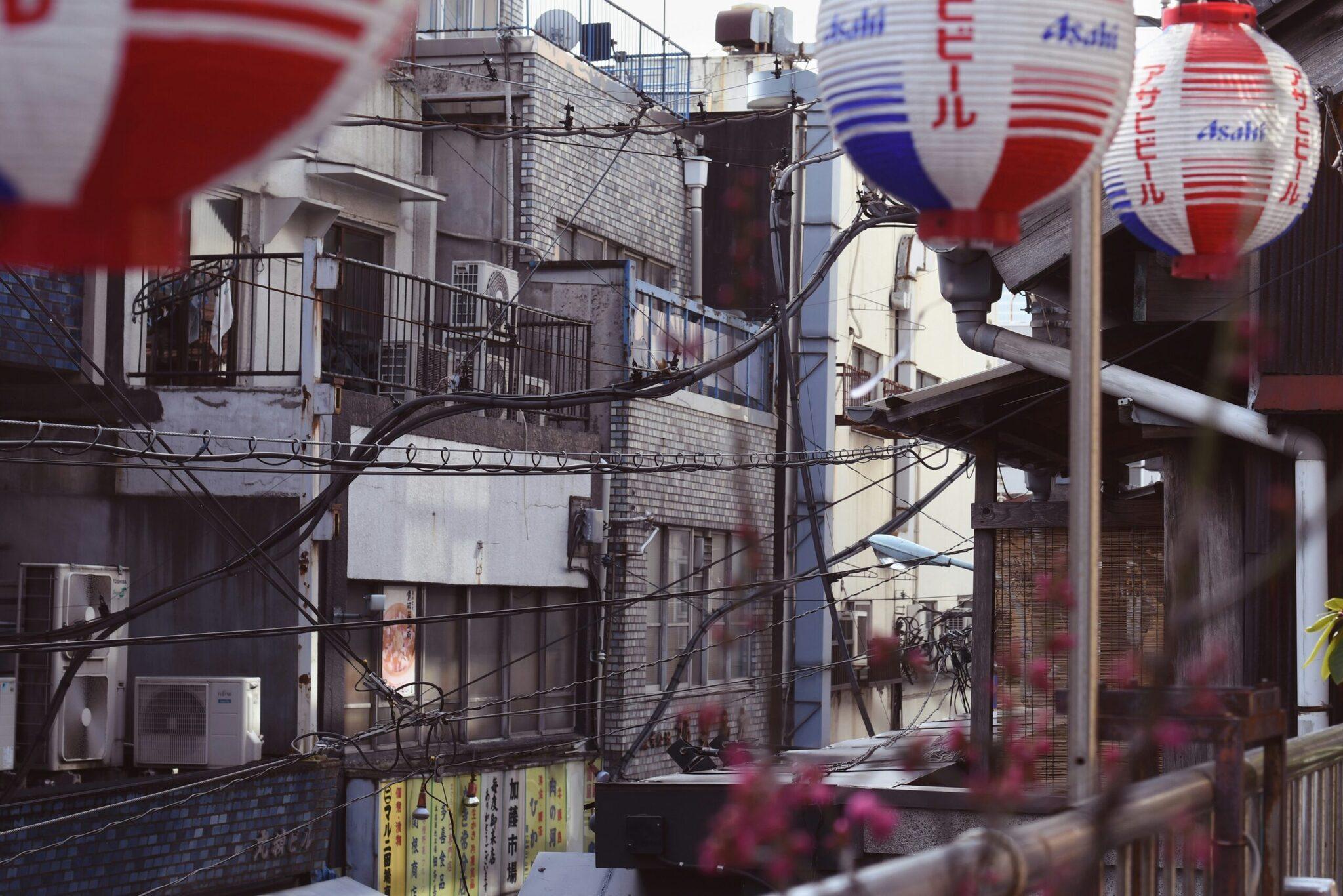 Una callejuela japonesa típica con faroles rojos y azules Asahi, cables eléctricos entrelazados y pequeños edificios residenciales tradicionales