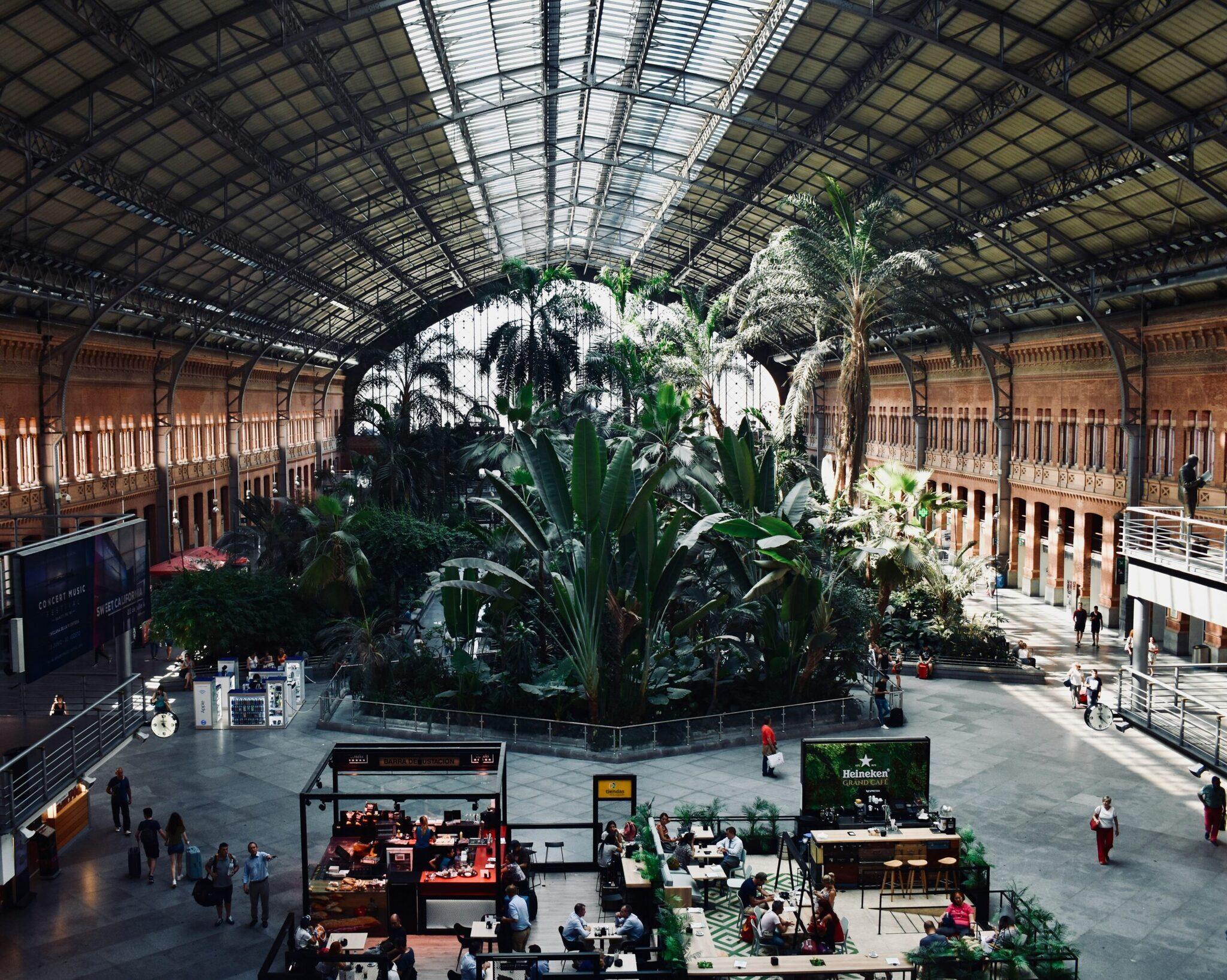 Vista aerea di una storica stazione ristrutturata con tettoia metallica, giungla interna e ristoranti, architettura vittoriana in mattoni rossi