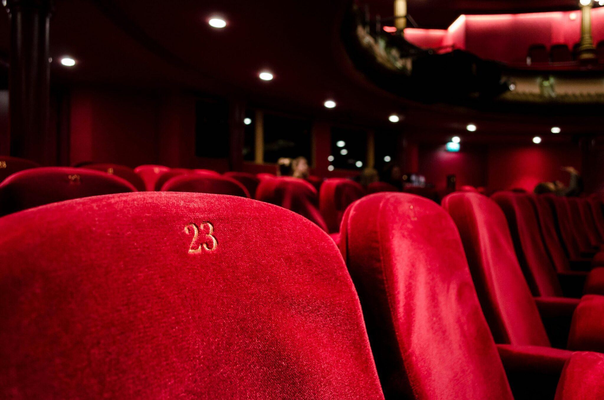 Fila di poltrone rosse numerate in un’elegante sala da spettacolo, con il sedile 23 in primo piano