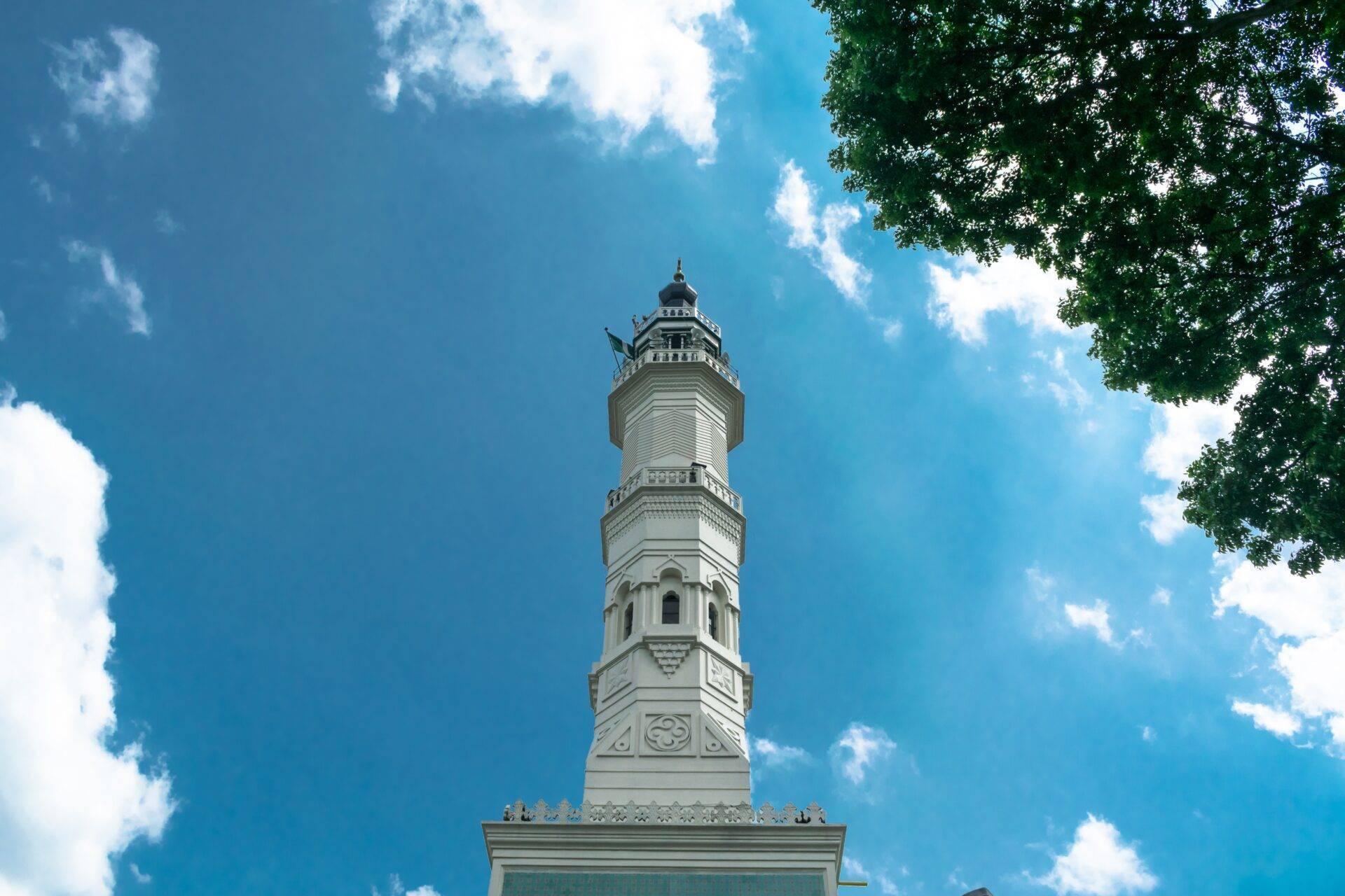 Torre bianca ornata in stile architettonico asiatico, fotografata dal basso verso l’alto sotto un cielo azzurro limpido