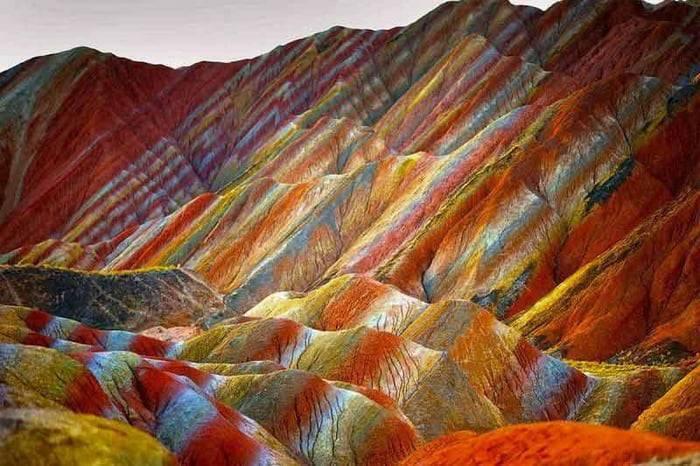 Montañas con estratos de colores rojo, naranja, amarillo y azul formando patrones geométricos espectaculares