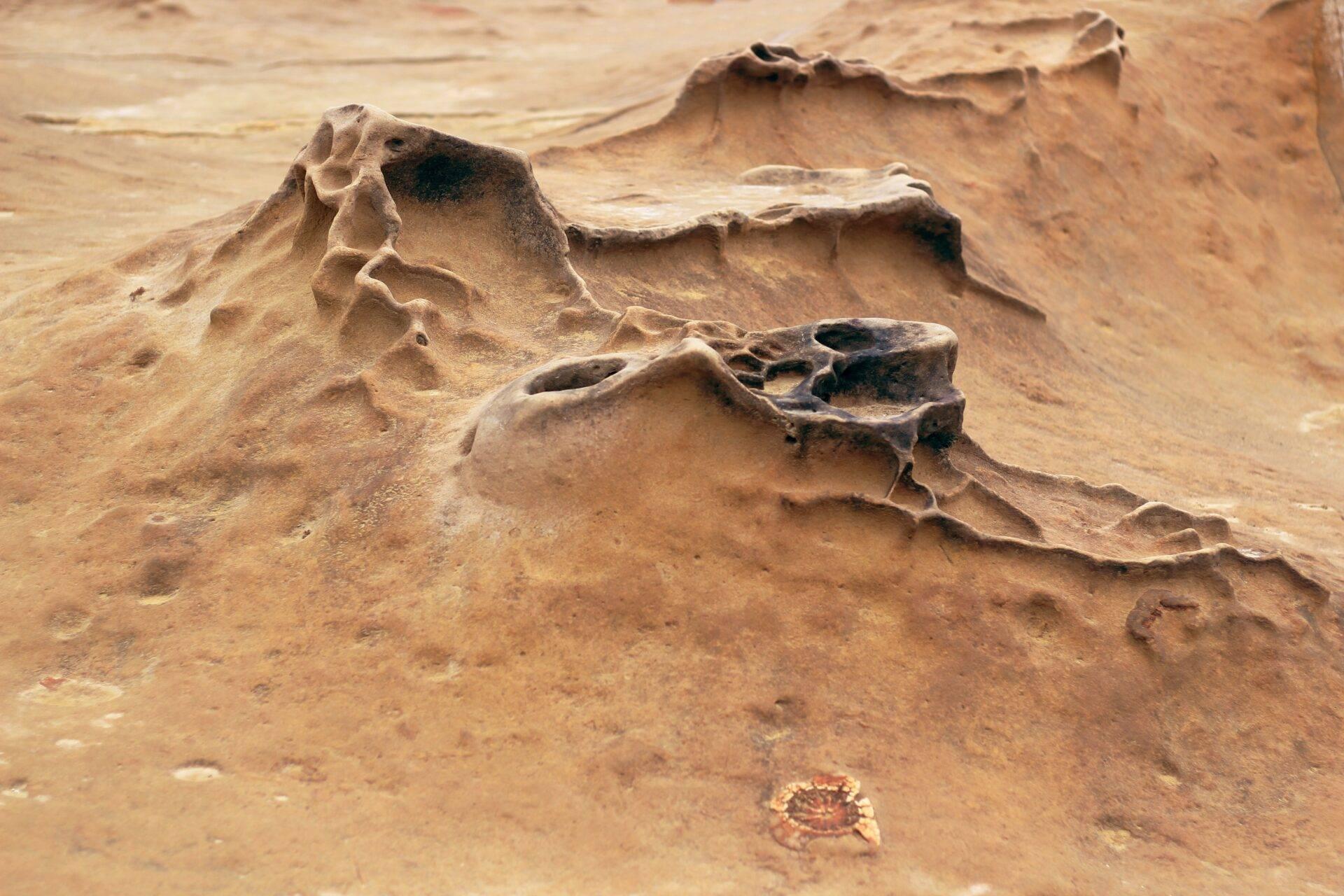Formazioni rocciose erose e scolpite in un paesaggio arido dalle tonalità ocra e beige