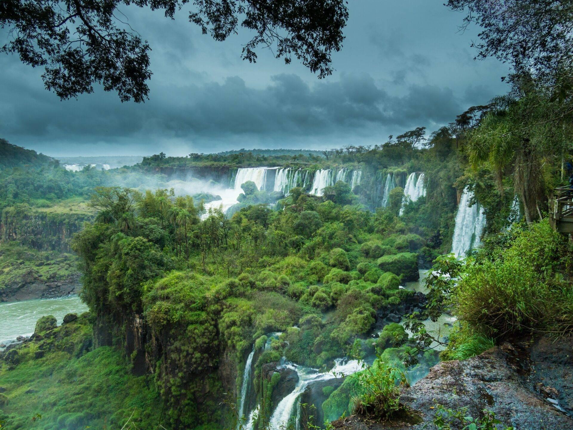 Cascata spettacolare circondata da giungla fitta con più salti d’acqua bianchissimi sotto un cielo nuvoloso