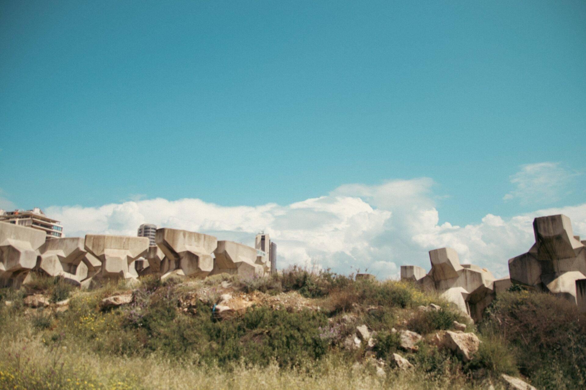 Ruinas de hormigón monumental con bloques geométricos sobre una colina rocosa bajo el cielo azul