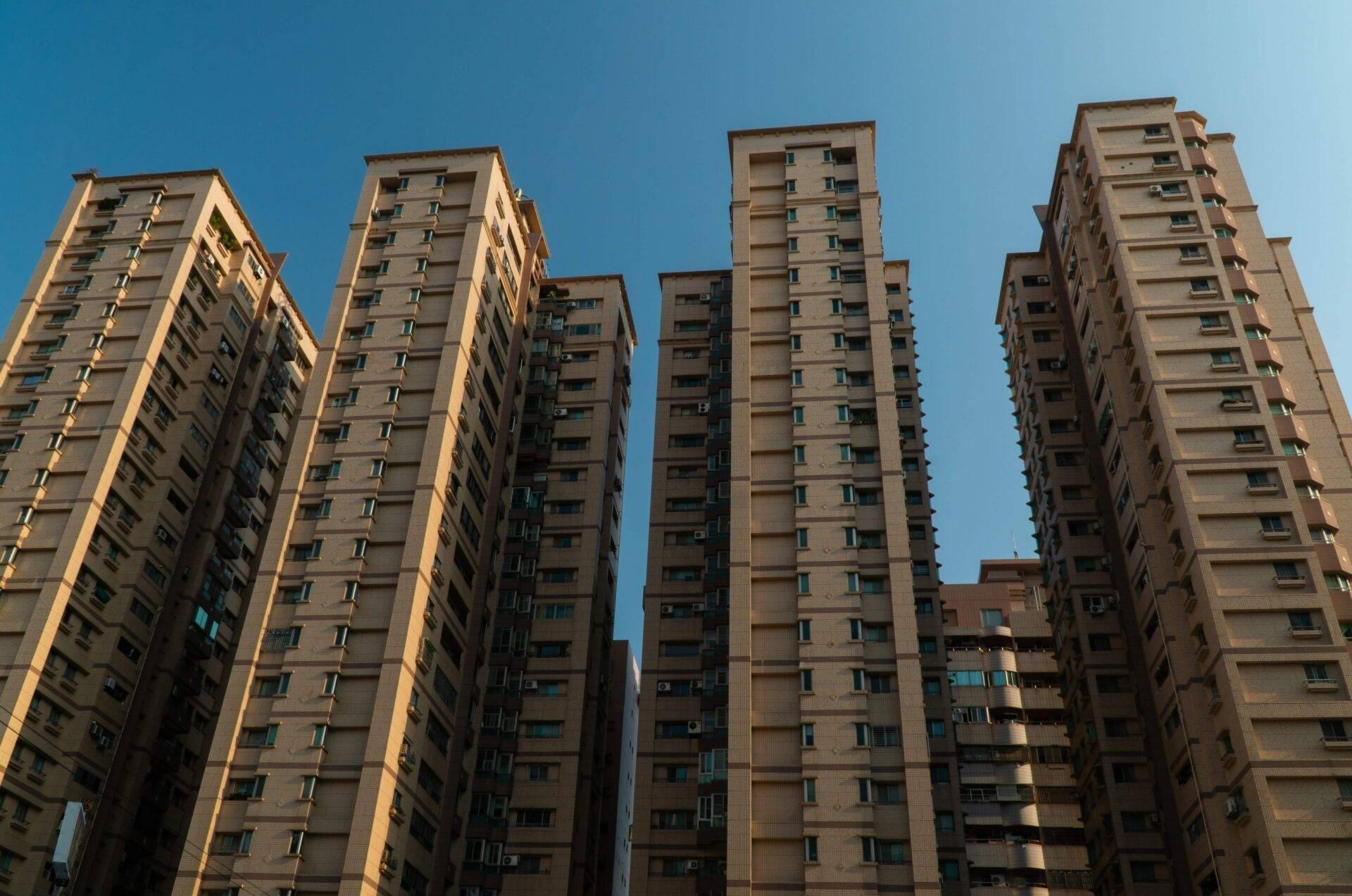 Palazzi residenziali moderni in cemento beige allineati sotto un cielo azzurro sereno in zona urbana