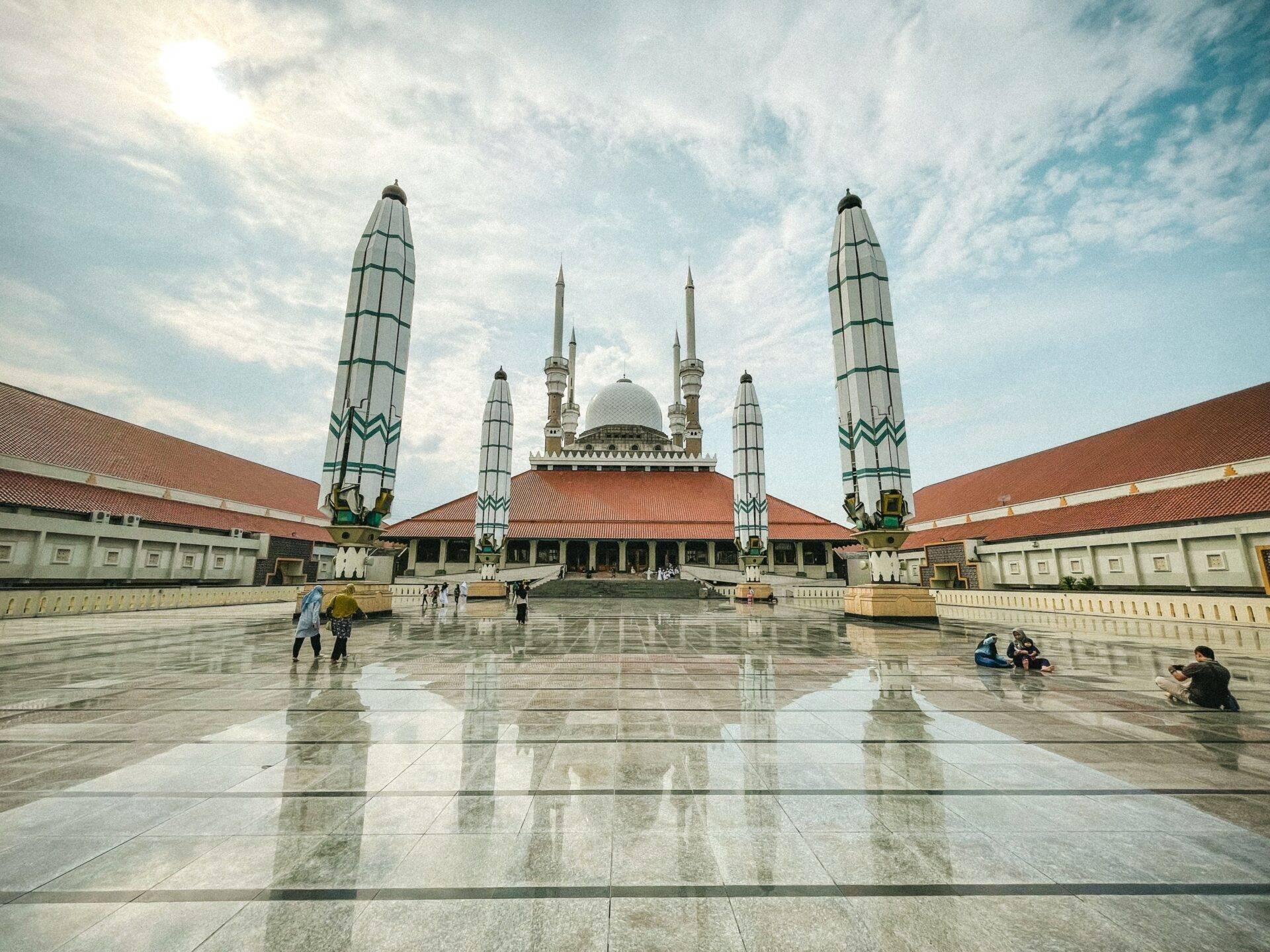 Grande moschea con cupola bianca e minareti ornamentali, corte lastricata riflettente e maestosa architettura islamica