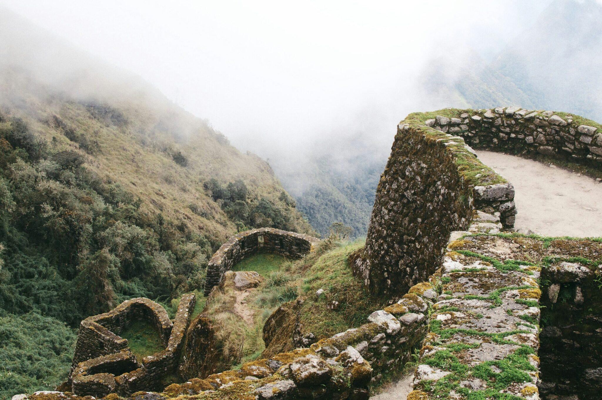 Ruines de pierre couvertes de mousse dans les montagnes péruviennes brumeux, entourées de végétation dense