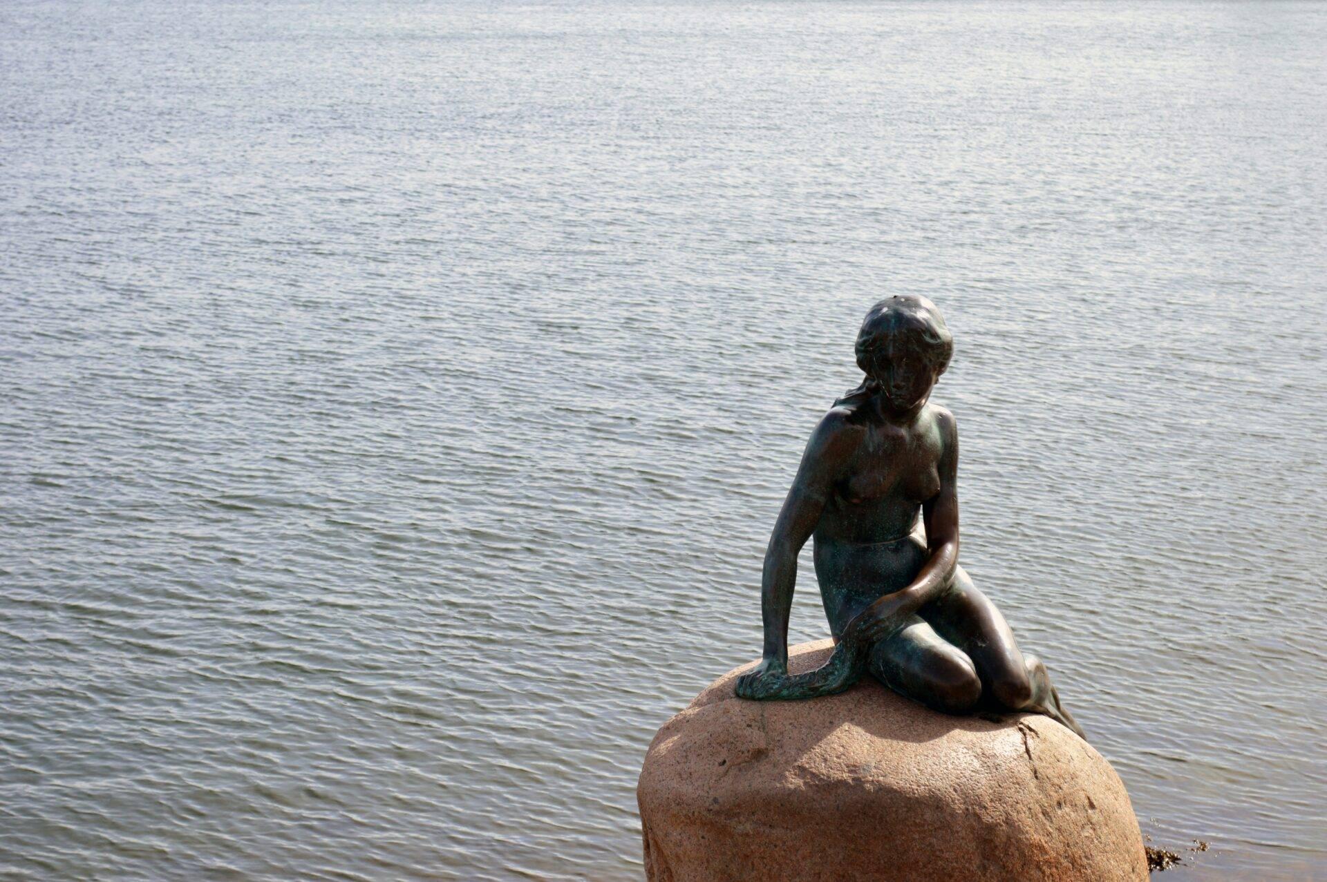 Statua della sirenetta seduta su uno scoglio di fronte al mare, celebre monumento turistico costiero
