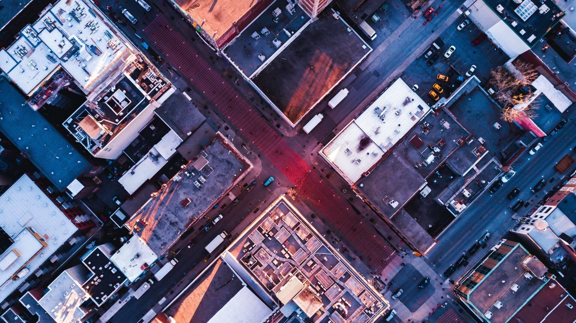 Luftaufnahme eines dicht bebauten Stadtviertels mit Gebäuden, bunten Dächern und sich kreuzenden Straßen