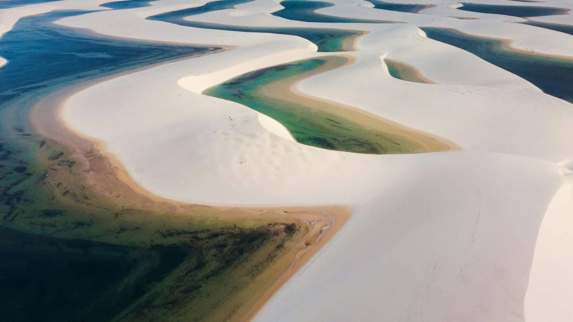 Vista aérea de lagos de agua turquesa y dunas de arena blanca formando un paisaje desértico surrealista