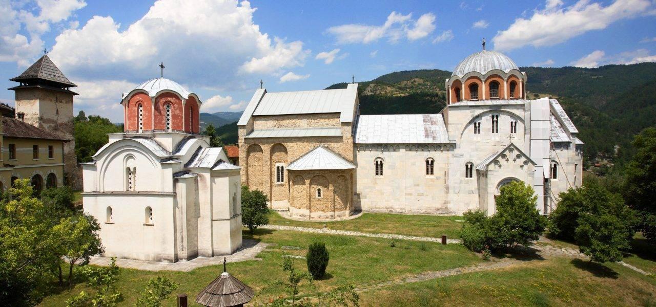 Orthodoxer Klosterkomplex mit Kirchen mit goldenen und weißen Kuppeln, umgeben von Grün und bewaldeten Bergen