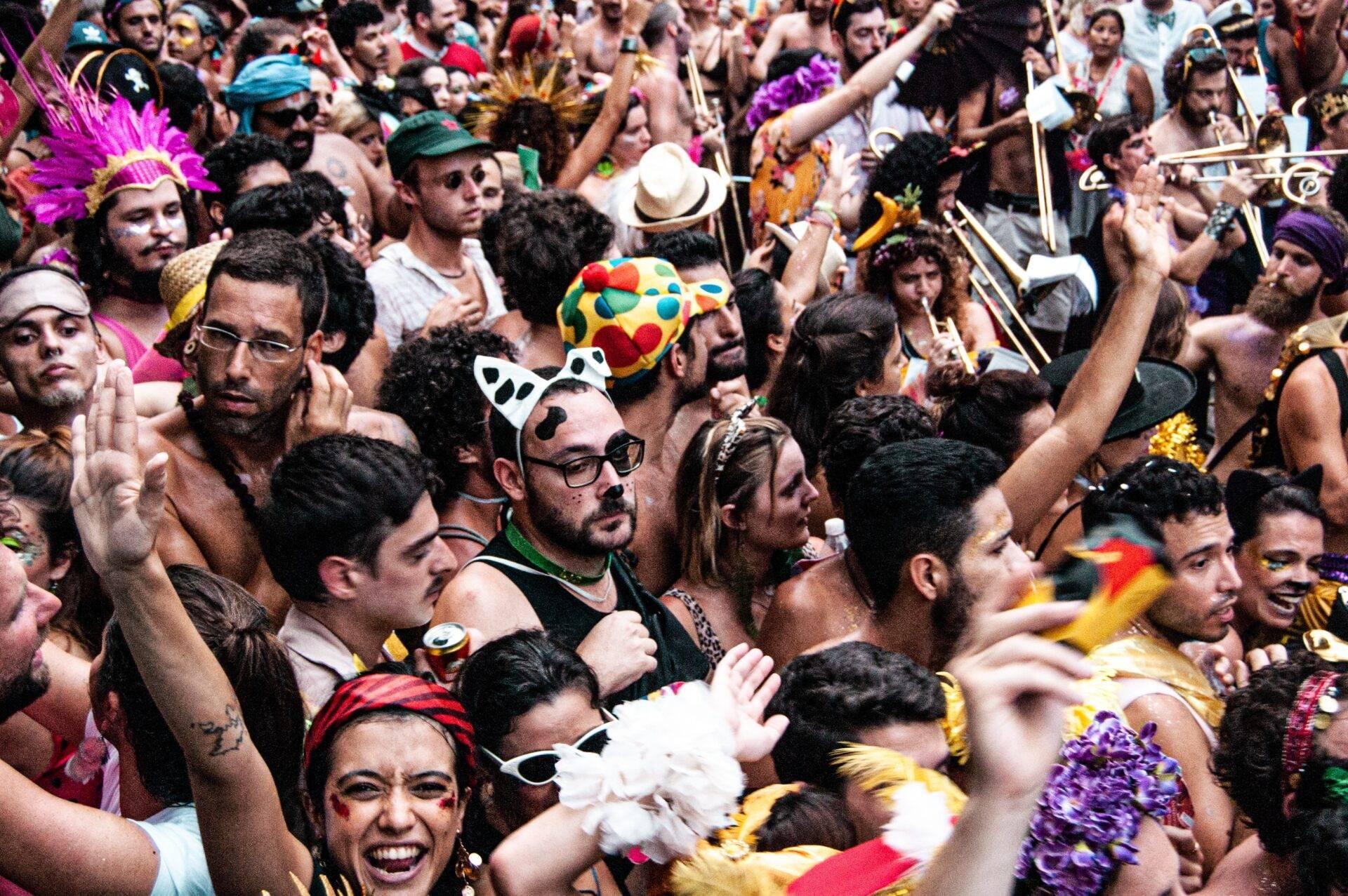 Una folla fitta e colorata in costume di carnevale con maschere, piume e accessori festosi