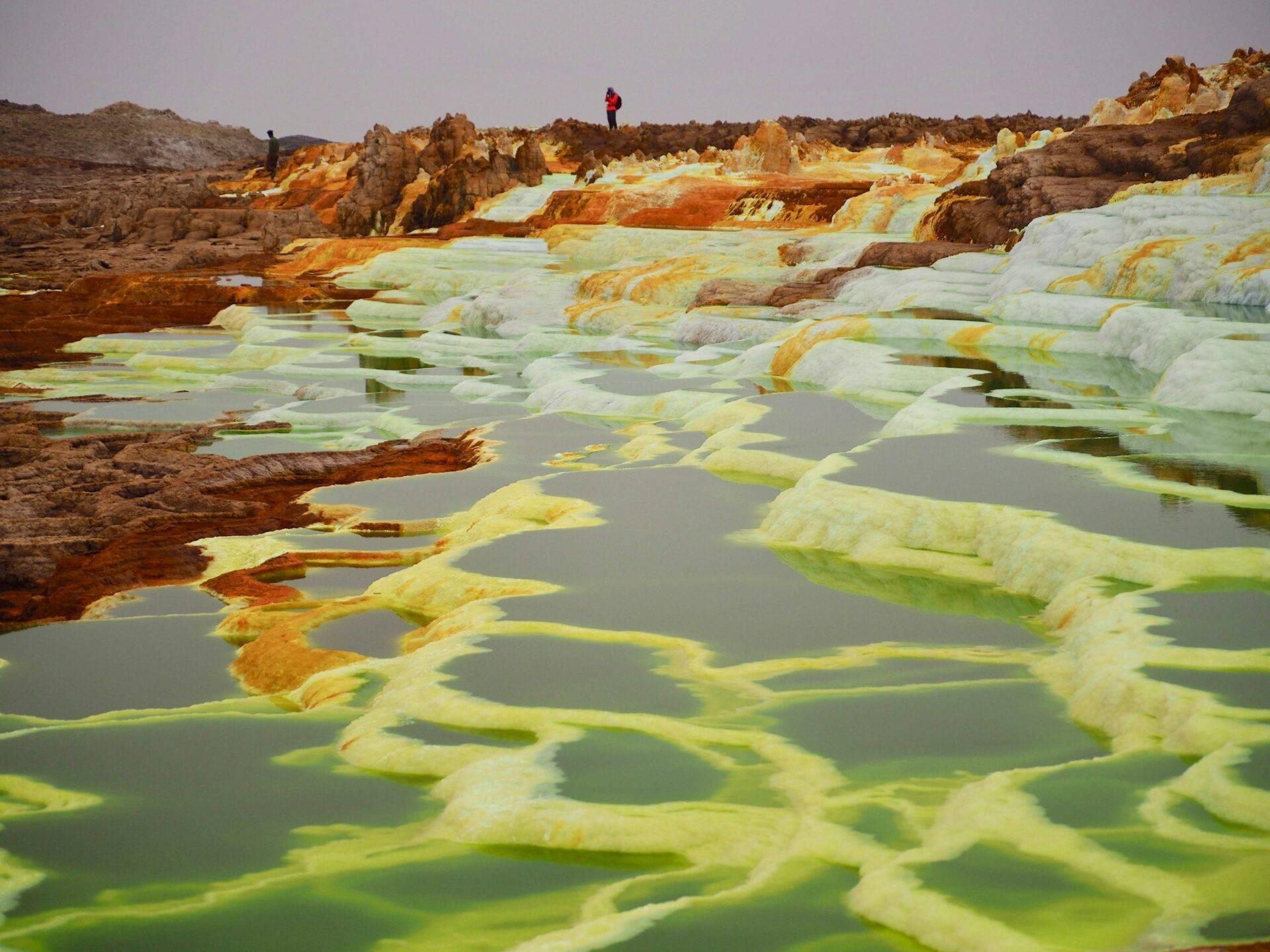 Geothermal pools with coloured mineral waters in yellow and green, with orange rock and mineral formations