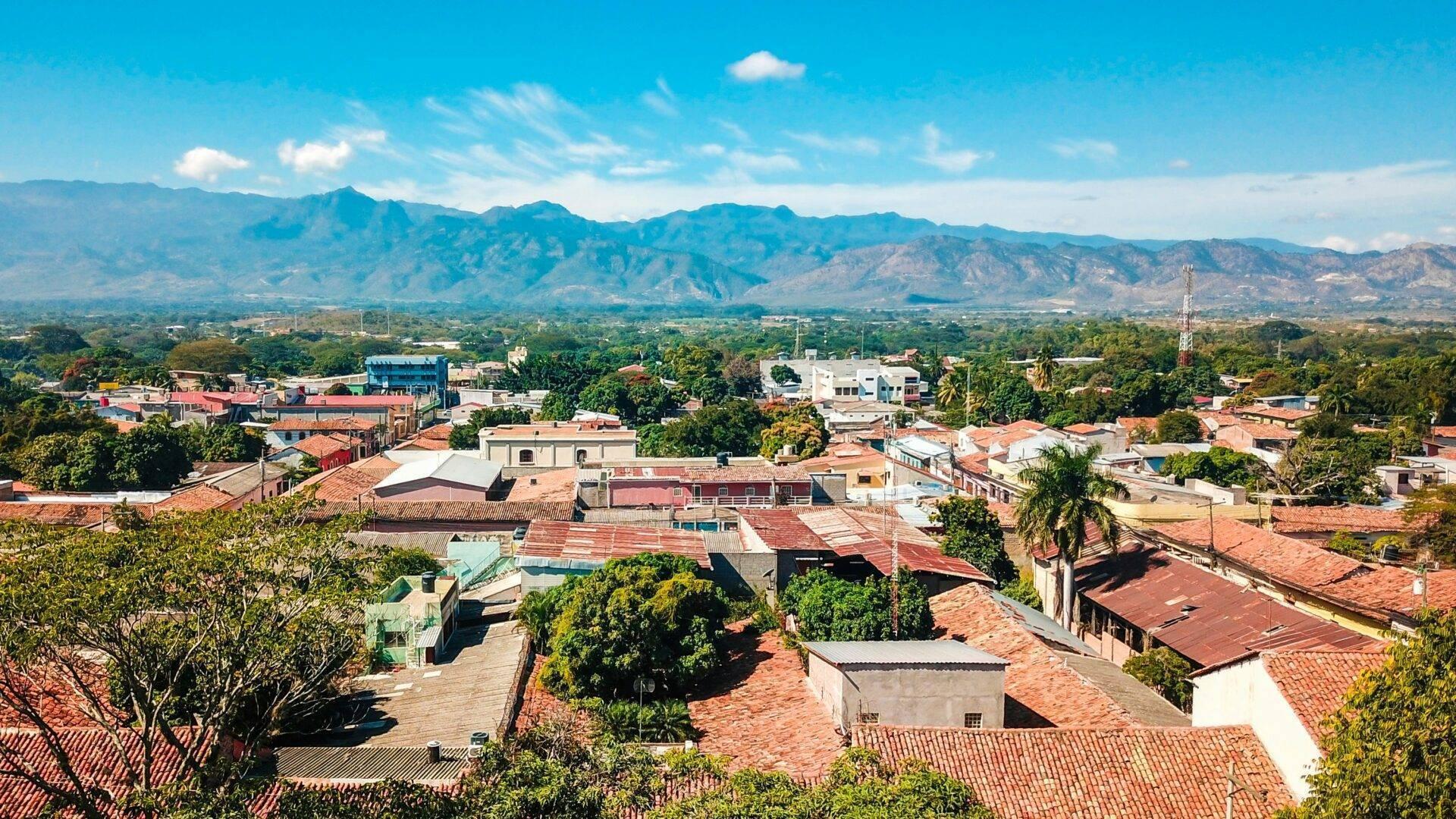 Vista panoramica di una piccola città coloniale con montagne verdeggianti sullo sfondo sotto un cielo azzurro