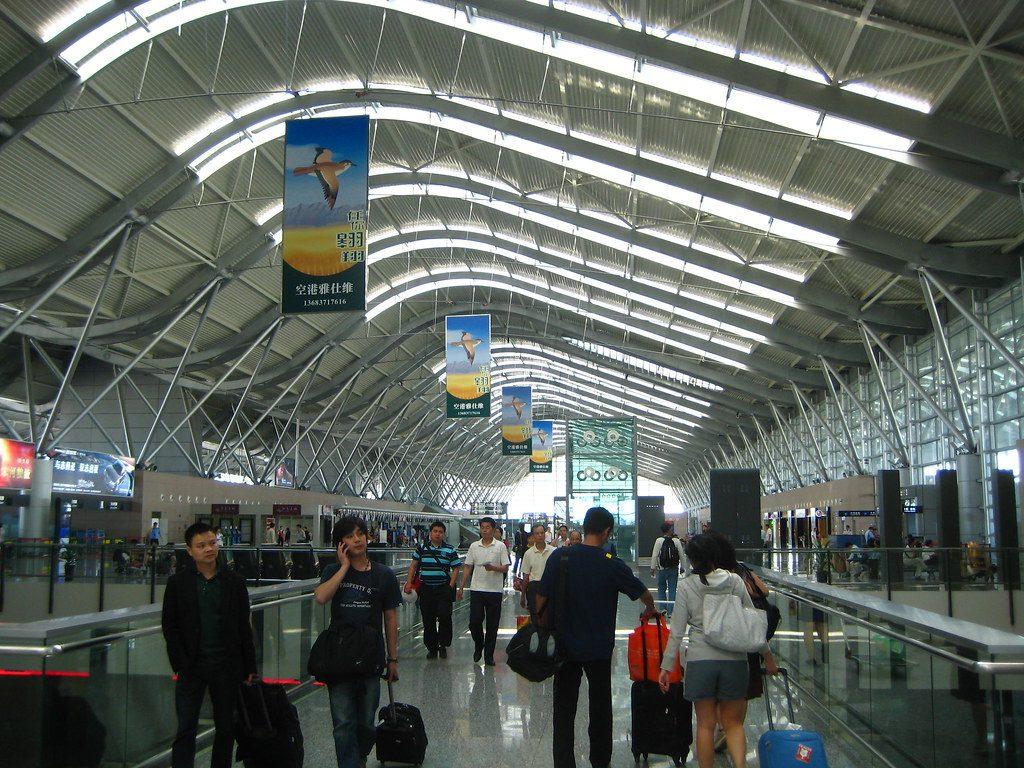 Travellers waiting in an airport terminal looking at departure boards showing delays